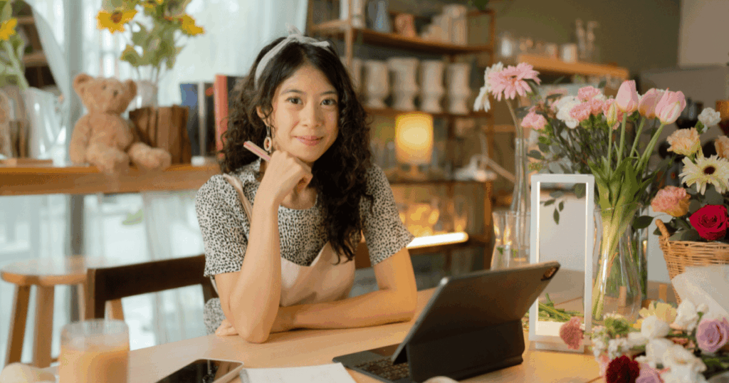 Mujer emprendedora gestionando la contabilidad de su negocio de flores en una tablet para evitar mezclar gastos personales.