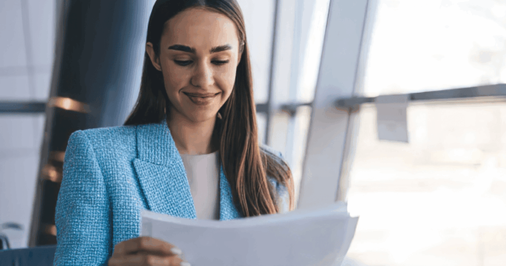 Mujer profesional sonriente revisando documentos para presentar la declaración complementaria del Modelo 303 de IVA.