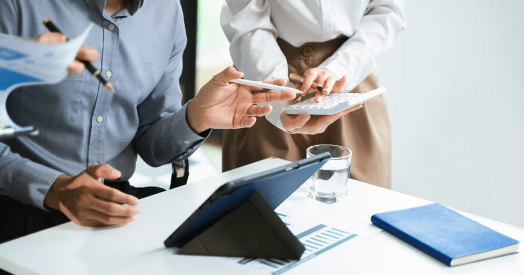 Tres profesionales revisando datos fiscales en una tablet y una calculadora para presentar una declaración complementaria y corregir errores en los impuestos.