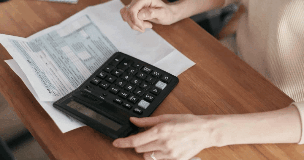 Manos de un contribuyente utilizando una calculadora negra sobre una mesa de madera para calcular cómo fraccionar pago renta.