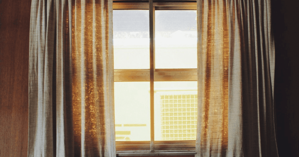 Fotografía de una ventana con cortinas beige que deja pasar la luz del sol, utilizada como metáfora visual para explicar qué es la Ventanilla Única del IVA (One Stop Shop) para autónomos que venden en la Unión Europea.