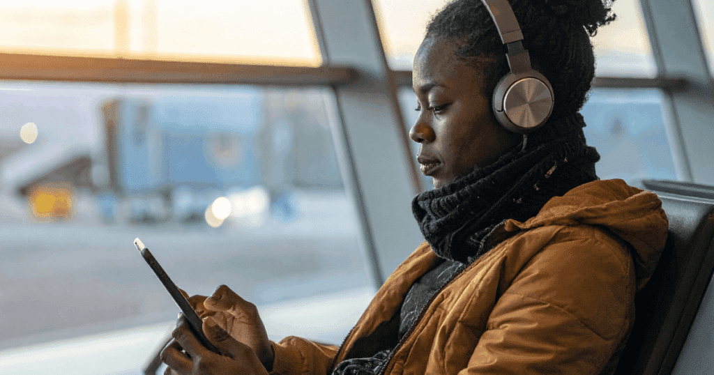 Una mujer autónoma con auriculares sentada revisa con atención el estado de su Renta en la pantalla del teléfono móvil.
