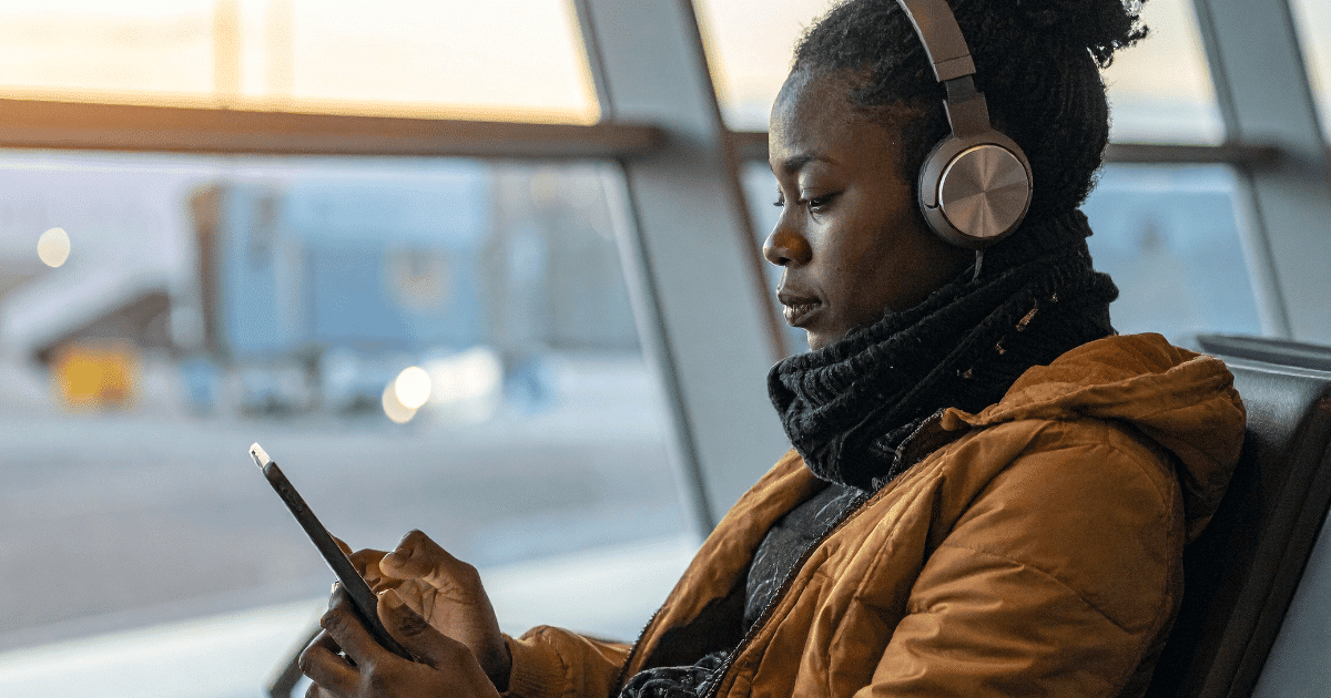 Una mujer autónoma con auriculares sentada revisa con atención el estado de su Renta en la pantalla del teléfono móvil.