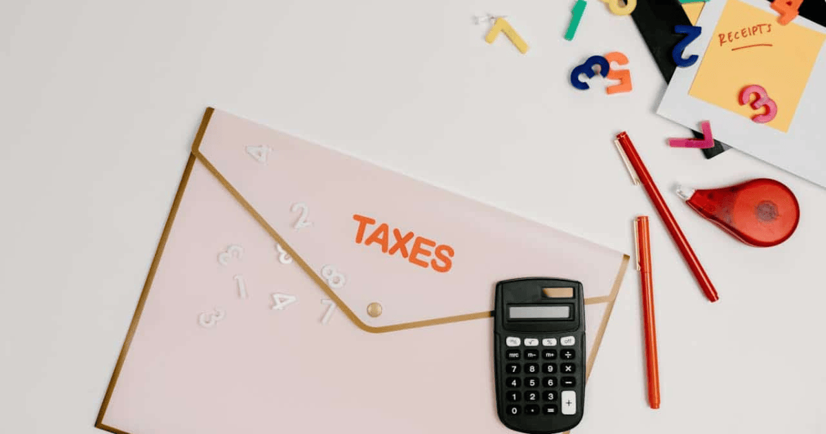 Vista superior de una carpeta con la palabra TAXES, calculadora, bolígrafos y notas de recibos para calcular cómo deducir el IVA de una factura simplificada o ticket.