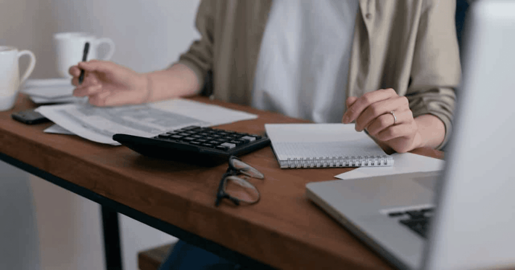 Autónomo calculando gastos en su escritorio con un ordenador portátil, representando el ahorro fiscal y cómo pagar menos impuestos legalmente
