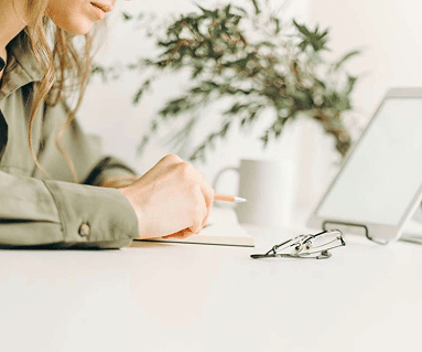 Persona tomando notas sobre su mesa de trabajo mientras prepara la documentación para el alta de autónomo en Hacienda y Seguridad Social.