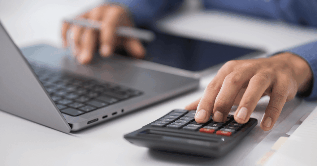 Un autónomo usando una calculadora y un portátil para organizar el calendario fiscal de abril 2026.